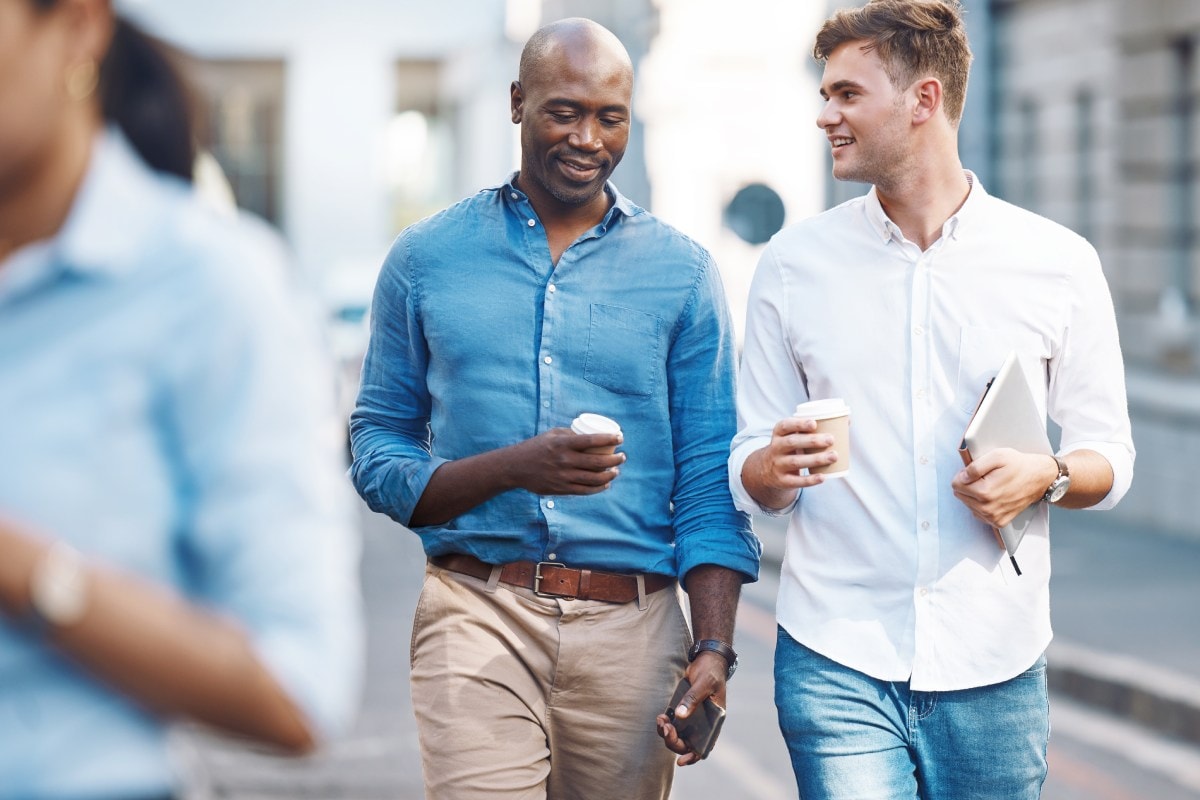 Twee mannen lopend in gesprek met laptop en koffie